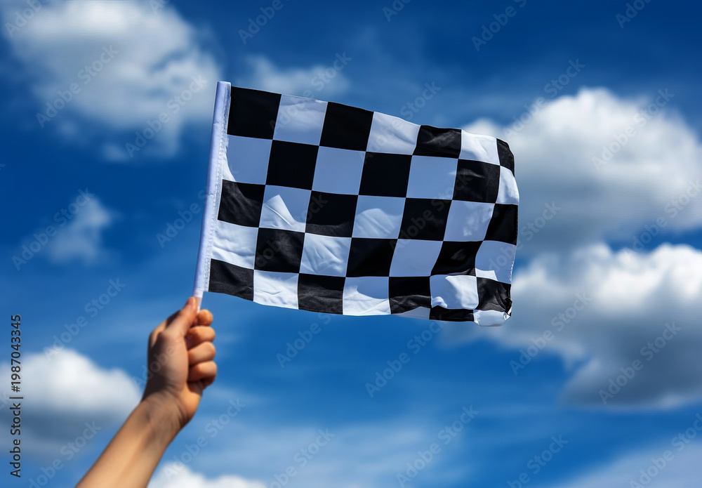 Fototapeta premium close-up of a hand holding a black and white checkered flag against a blue sky 