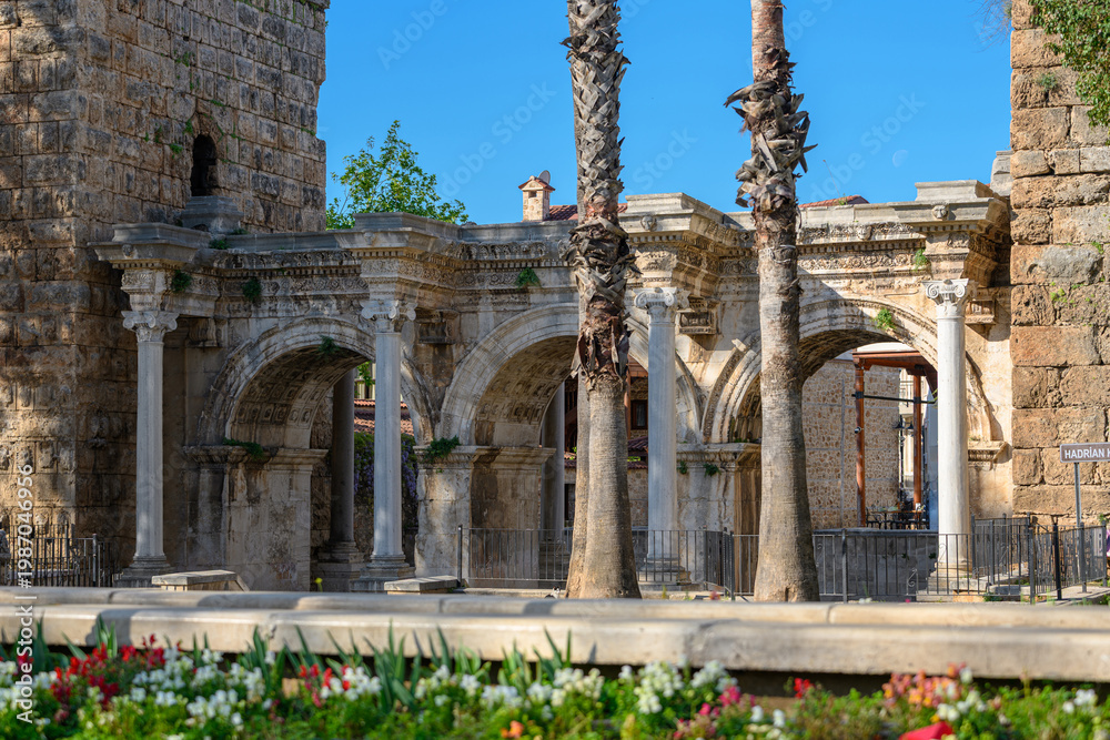 Fototapeta premium Historic Hadrian Gate surrounded by trees and flowers in Antalya city