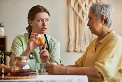 Canvas Print Young adult female caregiver explaining prescription medication to senior woman