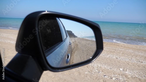 Reflection of serene beach scene in side mirror of parked vehicle, capturing the tranquil shoreline and gentle waves, illustrating a peaceful moment by the water