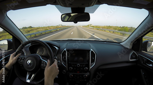 Driver's perspective from inside a car on a highway with clear road and green landscape visible on both sides, showcasing the journey ahead and the vehicle's interior details