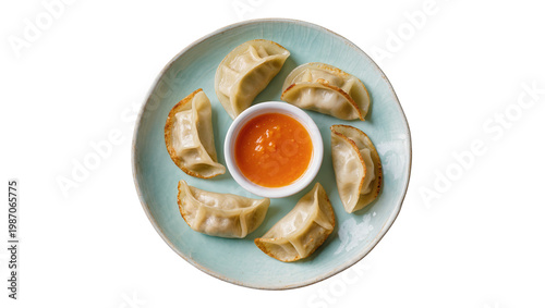 Six golden pan-fried dumplings with orange dipping sauce, isolated on transparent background