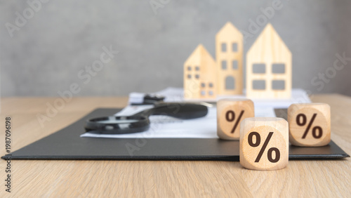 Multiple percentage signs on wooden blocks. Blurred background with houses, clipboard, and magnifying glass. Mortgage rate comparison concept.