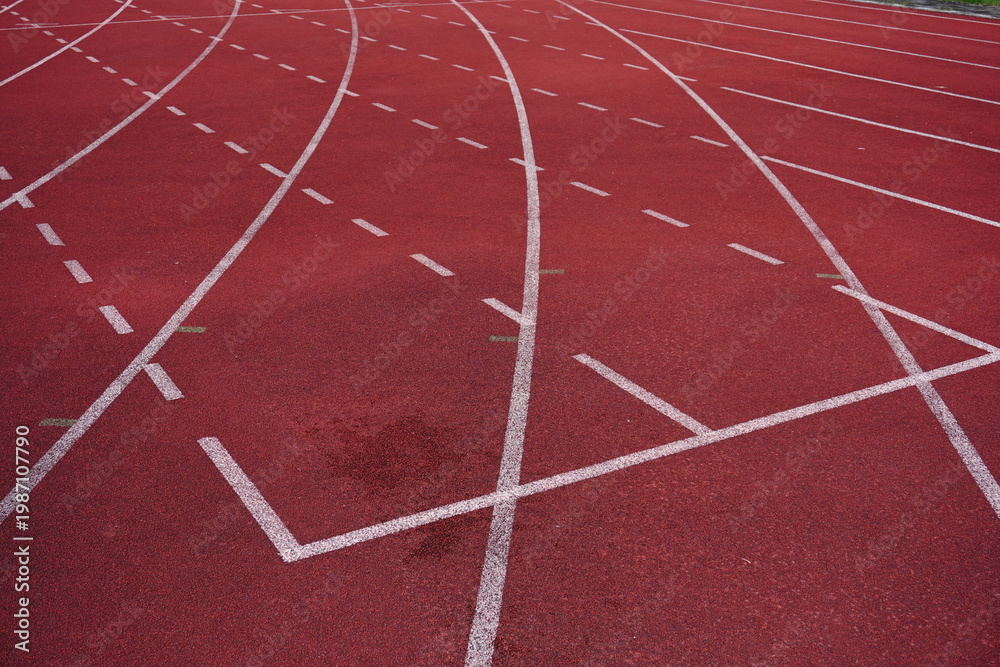 Fototapeta premium Red running track with white lane markings and dashed lines