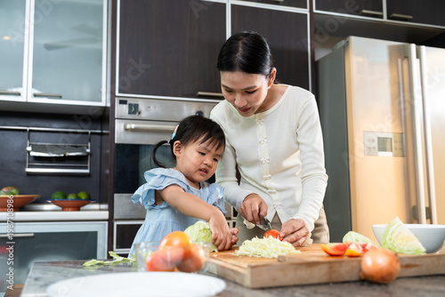 Culinary Bonding: A tender scene unfolds as a mother and child share a cherished moment in the kitchen, preparing fresh ingredients together for a wholesome meal.