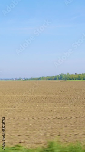 View from car side window of huge empty farm land on a sunny day slow