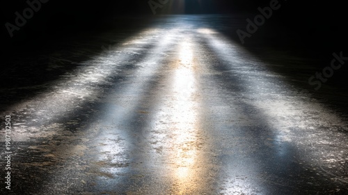 Streaking headlights illuminate a wet, reflective road surface at night creating a mesmerizing, illuminated path forward.