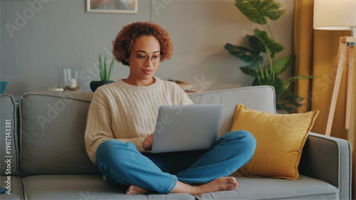 Young woman sitting on a couch with laptop in a cozy living room at home