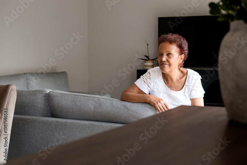 Portrait of a smiling senior hispanic woman relaxing in living room