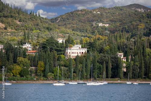 View from Lake Garda of coast, marina and promenade with Alps mountains in background, Garda, Garda Lake, Italy