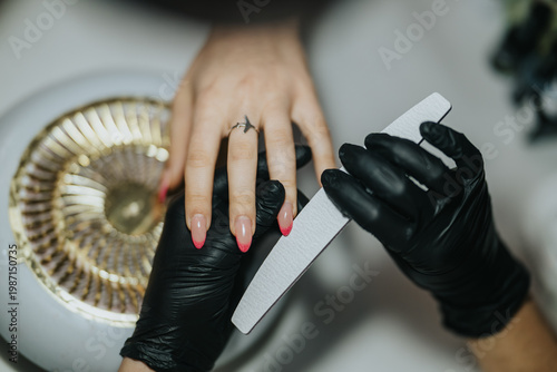Принти на полотні A manicurist files a client's pink ombré nails while holding the hand steady