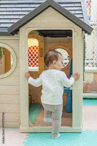 Toddler entering playhouse and exploring indoor playground