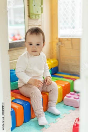 Toddler sitting on colorful blocks in daycare playroom