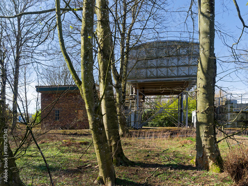 A back view of the Historical Steel Water Tanks at Stracathro Hospital Entrance, with a brick built workshop and metal railing fence.