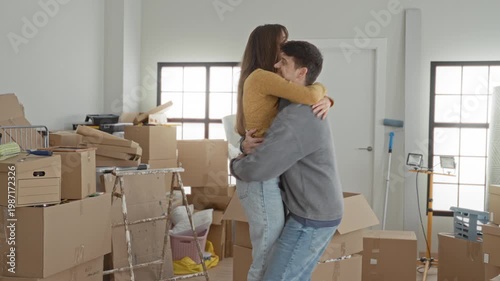 Wallpaper Mural Young man lifts woman in tight hug among stacked moving boxes and open cartons in building entry room; new home joy. Torontodigital.ca