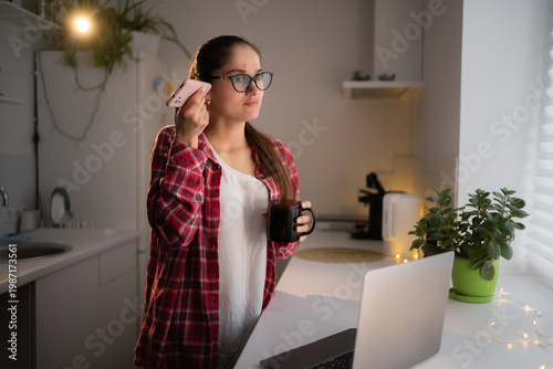 Fotografie Woman in eyeglasses listen voice message on smartphone using speaker phone listening voicemail at home