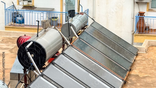 Rooftop solar water heating system with evacuated tube collectors and insulated storage tank, urban apartment building setting, renewable energy and sustainability concept