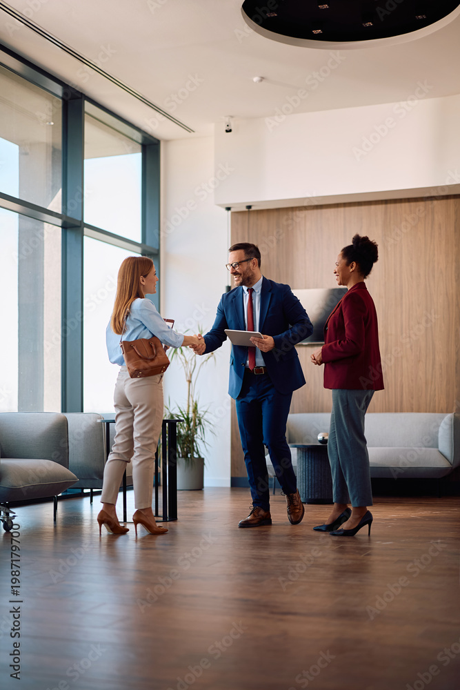 Fototapeta premium Happy embers of human resource team greeting job candidate in office lobby.