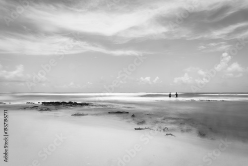 Person standing on coastal rocks facing ocean waves, serene mood