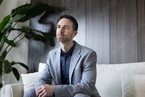 Businessman in Suit Pondering Thoughtfully on Sofa