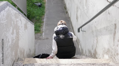 Lonely teenage boy sitting on outdoor stairs after school, isolated from others, symbolizing bullying and social exclusion. Concept of adolescence, sadness, and solitude in urban environment.