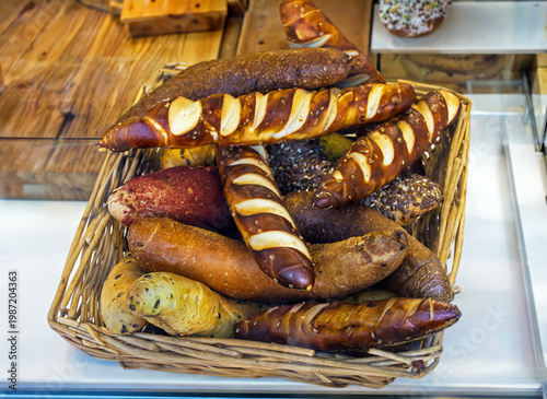 Pile of baked pastry rolls in rattan basket inside bakery interior counter