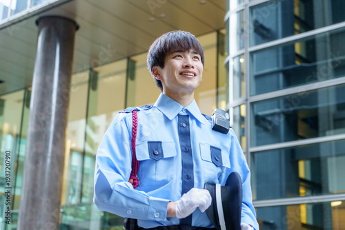 オフィスビルの前に立つ若い日本人男性警備員　撮影協力：学校法人電波学園　東京電子専門学校