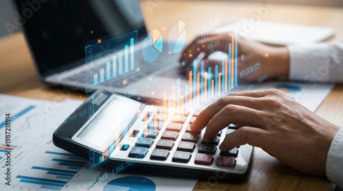 Business professional uses calculator and laptop to analyze financial data during work hours in an office setting