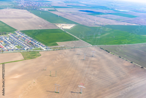 Aerial view of power lines and electricity pylons crossing agricultural fields.