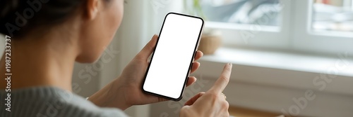 Woman holding smartphone with blank screen and pointing finger at device
