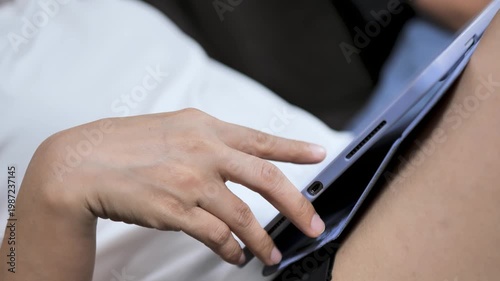Close-up of a woman using a tablet while touching the screen with one hand at home. The image reflects digital technology, online communication, mobile device use, entertainment, and modern lifestyle.