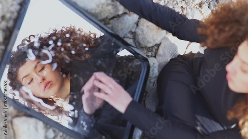 Young woman touching her reflection in a mirror outdoors