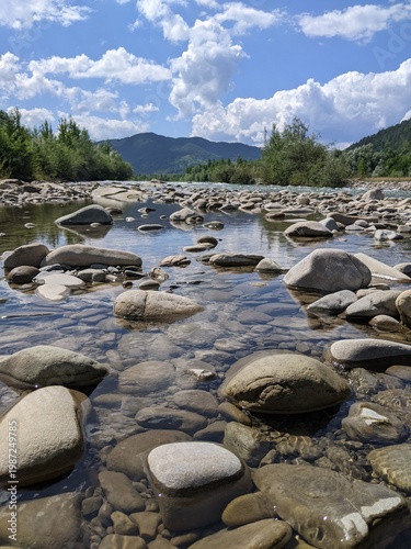 Purest transparent water in a mountain river flowing among the stones. Details of a sunny day in the mountains.