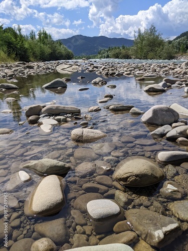 Purest transparent water in a mountain river flowing among the stones. Details of a sunny day in the mountains.