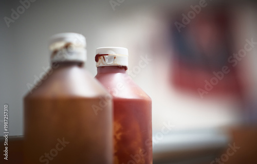 Close up of condiment bottles including ketchup, brown sauce, mustard and oil on a cafe counter, representing fast food culture, takeaway dining
