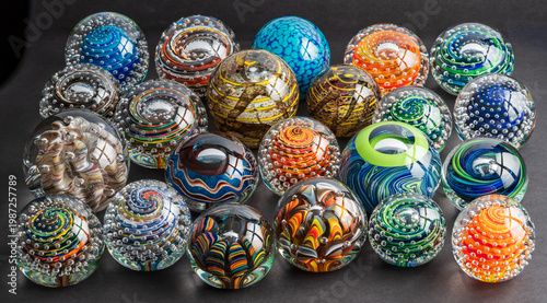 Fotografie A Bunch Of Handcrafted Glass Paperweights On A Black Backdrop