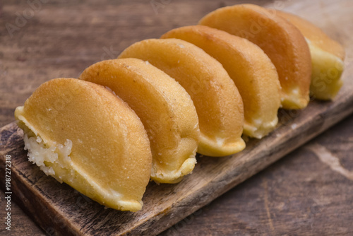 Freshly Baked Indonesian Kue Pukis – Traditional Golden Sweet Street Food Snack Served on a Rustic Wooden Board