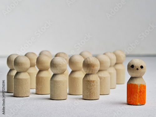 Wooden peg figures represent leadership, teamwork, and individuality with one figure standing out among the crowd on a neutral background