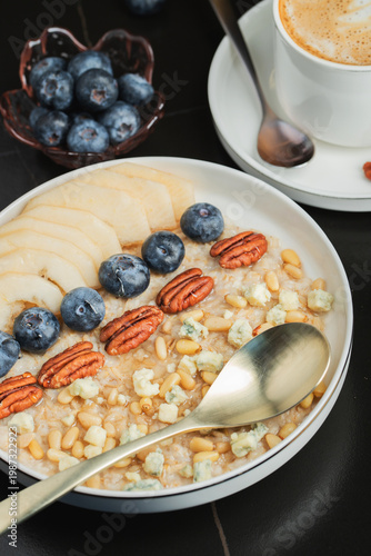 Oatmeal. Bowl of oatmeal porridge with blackberry, bananas and chia seeds on gray concrete old table background. Top view in flat lay style. Natural ingredients. Hot healthy breakfast and diet food