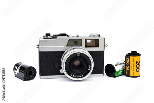 Collectibles vintage retro photography analog hobby concepts. Silver rangefinder camera with 40mm lens with black, yellow, and green rolls of 35mm color print film isolated on white background.