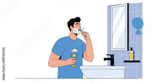 Young man in a blue t-shirt shaving his face with a razor and foam while looking in a bathroom mirror with blue tiles.