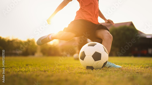 Action sport outdoors of kids having fun playing soccer football for exercise under the twilight sunset sky. Picture with copy space.