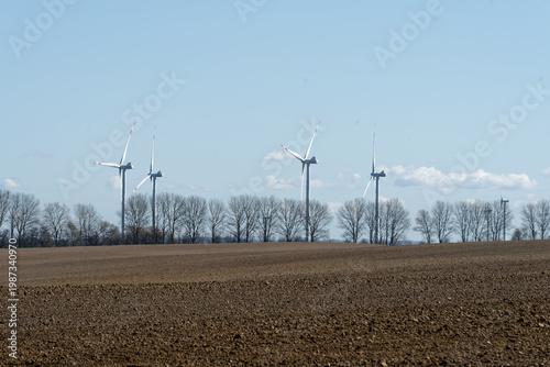 Wind turbines generating clean energy over ploughed field in Germany