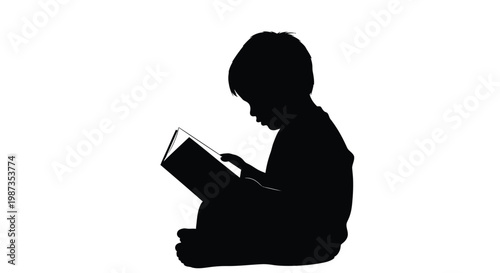 A young child intently reading a book captured in dark silhouette