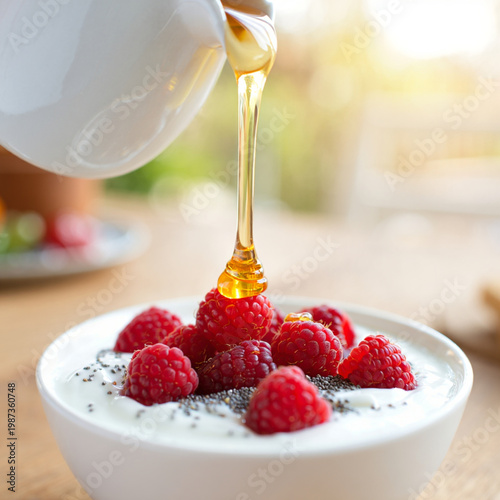 Close-up of Greek yogurt bowl with raspberries, chia seeds and golden honey drizzle, soft bokeh background in sun-drenched breakfast nook