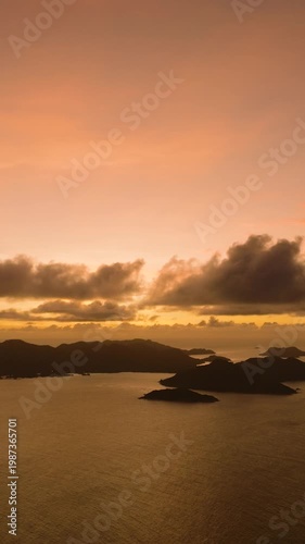Golden sunset over distant islands with a cloudy sky and calm ocean waters. Seychelles.