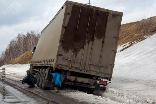 A road accident. A truck fell into a ditch on a country road in winter.