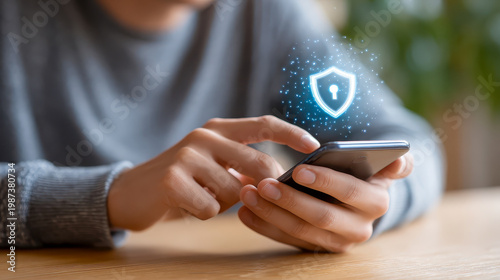 Close up of person using smartphone with glowing blue digital shield icon, cybersecurity, data protection, mobile privacy safety, and secure network connection concept.