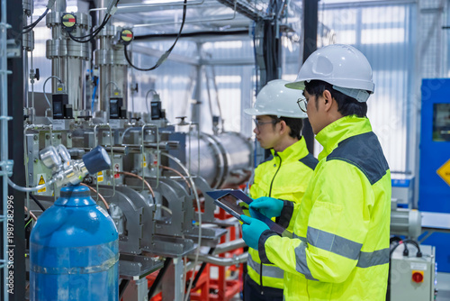 Professional engineers inspecting industrial gas control system and high pressure cylinders in technical laboratory. Focused on safety compliance, energy management, and maintenance maintenance.