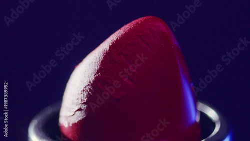 Lipstick closeup. Close inspection of vibrant red lipstick surface. Product portrayal highlighting texture and glossy finish under studio lighting
